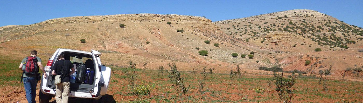 Two researchers taking kit out of their van in a field in Morocco