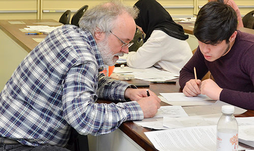 A male researcher explaining something to a male student on paper